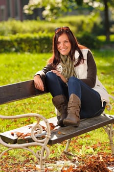 Autumn fashion outfit attractive woman sitting on park bench sunset