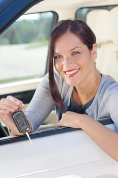 Attractive elegant businesswoman in new car showing keys smiling