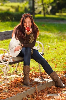Autumn fashion smiling beautiful woman eat apple sunset nature park