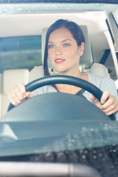Attractive elegant businesswoman driving luxury new car smiling behind window