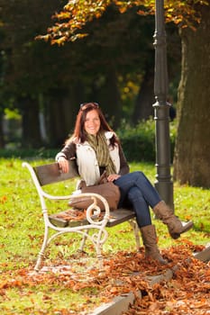 Autumn fashion outfit attractive woman sitting on park bench sunset