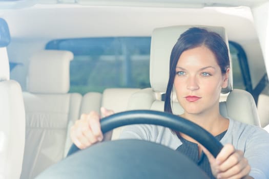 Attractive elegant businesswoman driving luxury new car smiling behind window