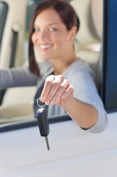 Attractive elegant businesswoman in new car showing keys smiling