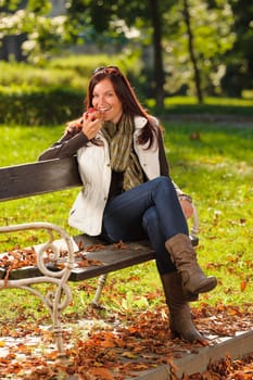Autumn fashion smiling beautiful woman eat apple sunset nature park