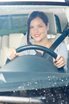 Attractive elegant businesswoman driving luxury new car smiling behind window
