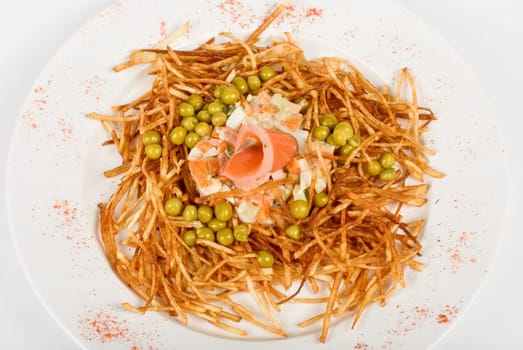 Closeup of salad with salmon fish at fried sliced potato with carrot and peas dressed by tomato sauce with cognac