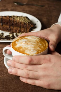Closeup of female hands holding cup of Cappuccino