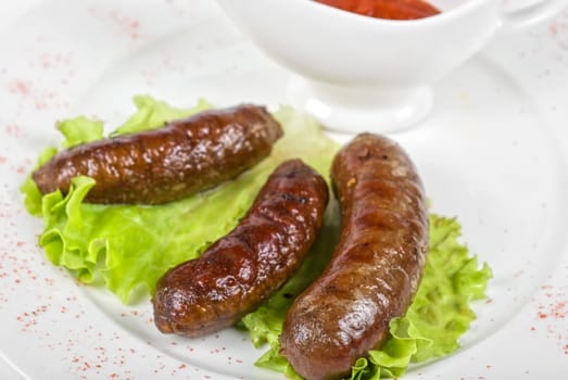 grilled venison sausage on a white with lettuce and sauce