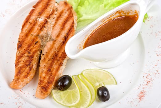 Grilled salmon steak with sauce,greens, lemon and olive