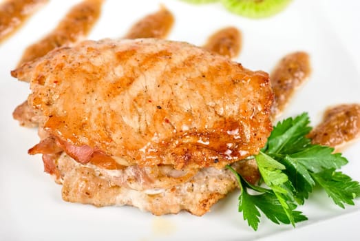 Cooked pork chop with kiwi and parsley on a white