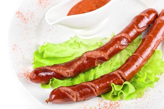 grilled sausage closeup with lettuce and sauce isolated on white