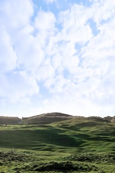 players and a flag waving on a hole on a links golf course in ireland