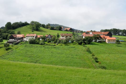 green landscape with a country village over hilly fields, germany