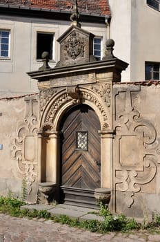 detail of baroque portal in stone with decorated frieze in ancient city centre