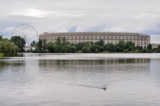 view of remains of nazi congress hall reflecting in lake under thunderclouds
