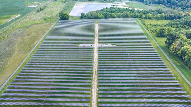 Image of Rows of solar panels in solar field aerial with swamp land in distance