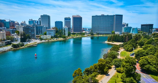 Image of Lone sailboat on Lake Merritt with aerial of downtown Oakland buildings in California