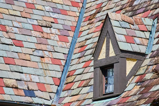 Image of Varying red and blue tiles on roof with tiny triangle shaped roof over tiny window