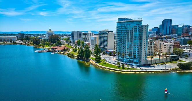 Image of Aerial downtown Oakland over Lake Merritt with loan sailboat on water on gorgeous summer day