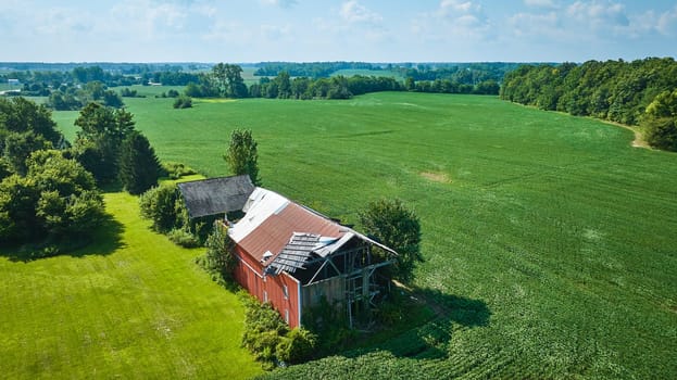 Image of Soybean farm with brown barn and red barn with partially blown off roof aerial