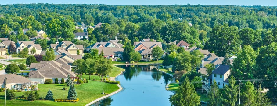 Image of Low panorama aerial over pond with houses around it on sunny day