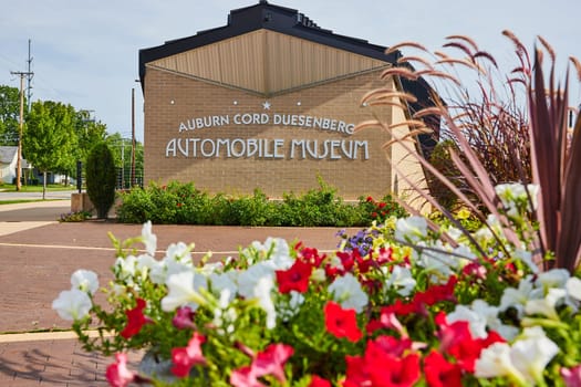 Image of ACD museum sign in front of red and white flowers in pot