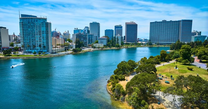 Image of Lake Merritt aerial with boats on water and skyscrapers across the way from small waterfront park