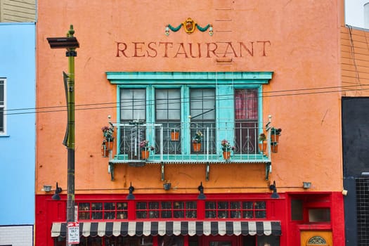 Image of Restaurant building with red paint on bottom and orange on top with teal bay windows