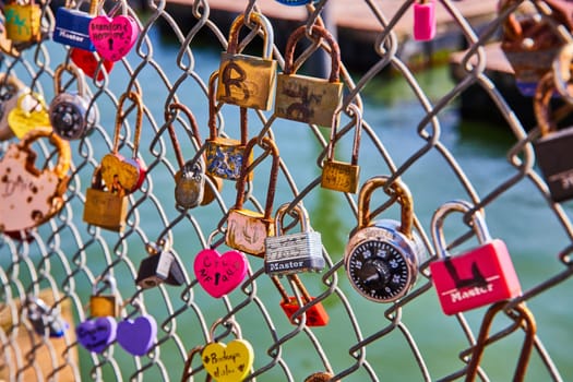 Image of Variety of love and heart shaped locks on chain link fence with water in background