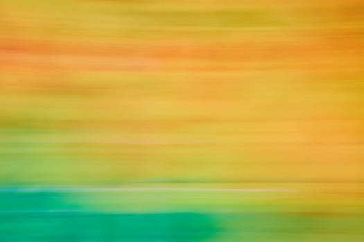 Image of Abstract streaks of pastel orange and yellow blurred with green on bottom