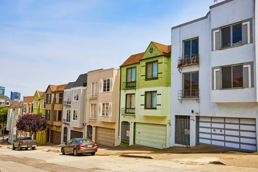 Image of Side by side houses along street with two vehicles and one house split between dark green and light