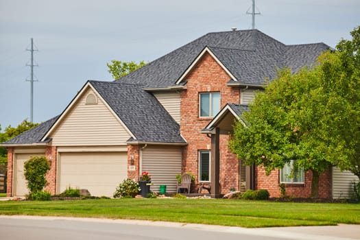 Image of Suburban home with reddish brown brick face and overhang over front door side view