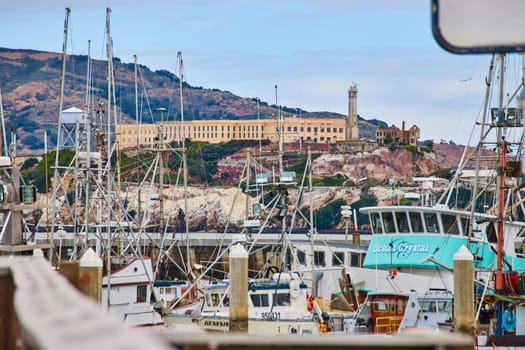 Image of View of Alcatraz prison building on top of hill seen through ship masts