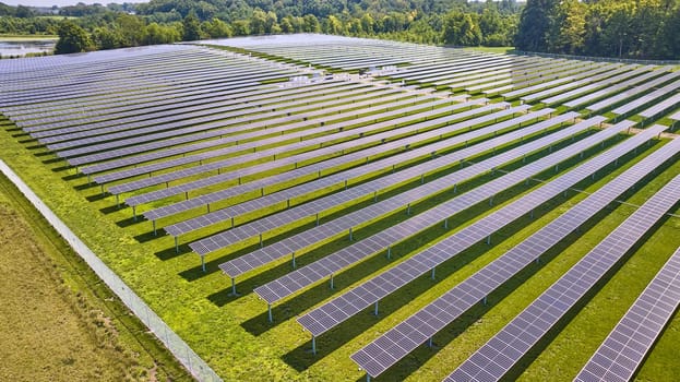 Image of Green grass around rows of solar panels on farm in Midwest aerial