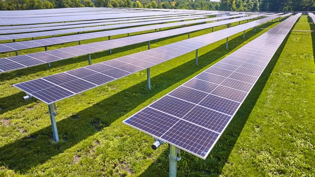 Image of Close up solar panels fading into long rows in aerial over farm