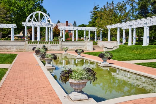 Image of Side view of water pool along stone path leading to gorgeous outdoor wedding spot with pergola