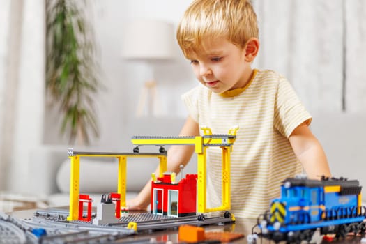 Child boy playing and building with colorful plastic bricks at the table. Early learning and development