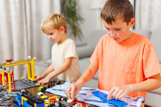 Two children playing and building with colorful plastic bricks at the table. Early learning and development.