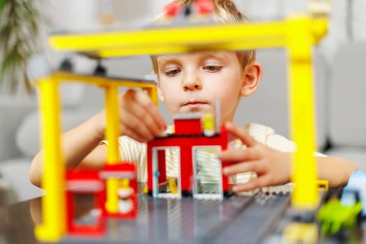 Child boy playing and building with colorful plastic bricks at the table. Early learning and development