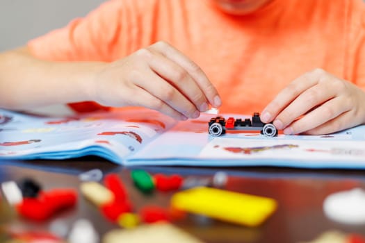 Child boy playing and building with colorful plastic bricks at the table. Early learning and development