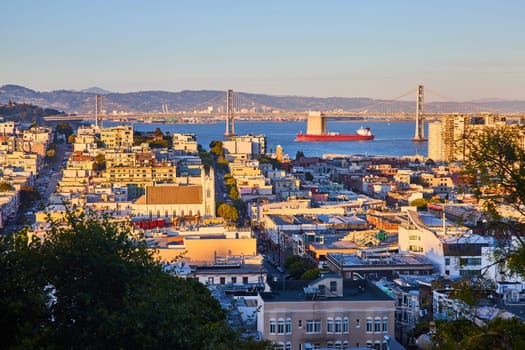 Image of Sunset glow over residential San Francisco city with tanker in bay under Oakland Bay Bridge