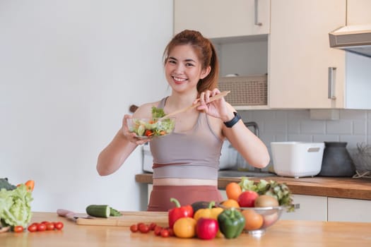 Young athletic woman is preparing a healthy organic vegetable salad in a modern kitchen at home..