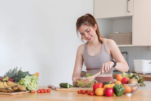 Young athletic woman is preparing a healthy organic vegetable salad in a modern kitchen at home..