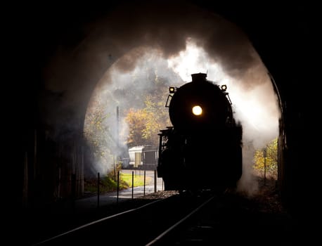 Old steam train pulling into a tunnel belching steam and smoke