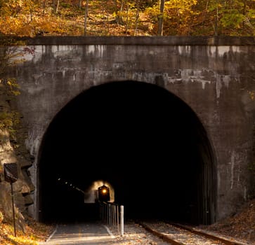 Old steam train pulling into a tunnel belching steam and smoke