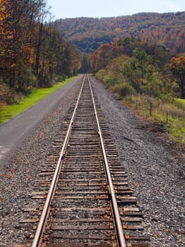 Cycling and hiking path besides railway lines in rural mountains in autumn
