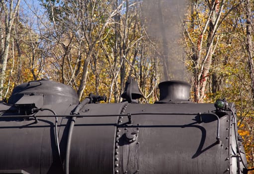 Old steam locomotive pulls freight through rural countryside in autumn