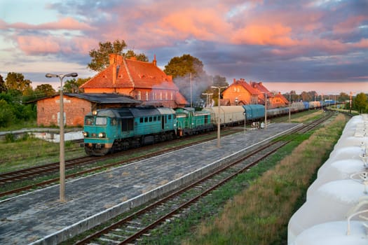 Freight train hauled by the diesel locomotive passing the station
