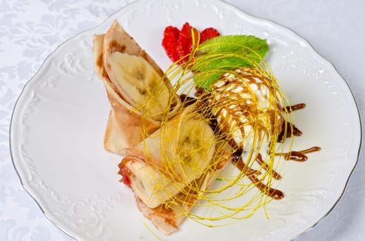 Dessert of pancake with banana, ice-cream, caramel, strawberry and mint