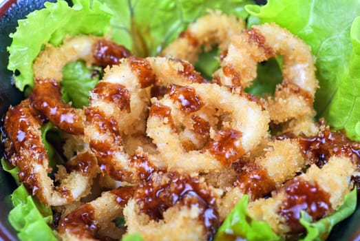 Deep-fried squid with salad leaves, sauce, green and lemon on a white background